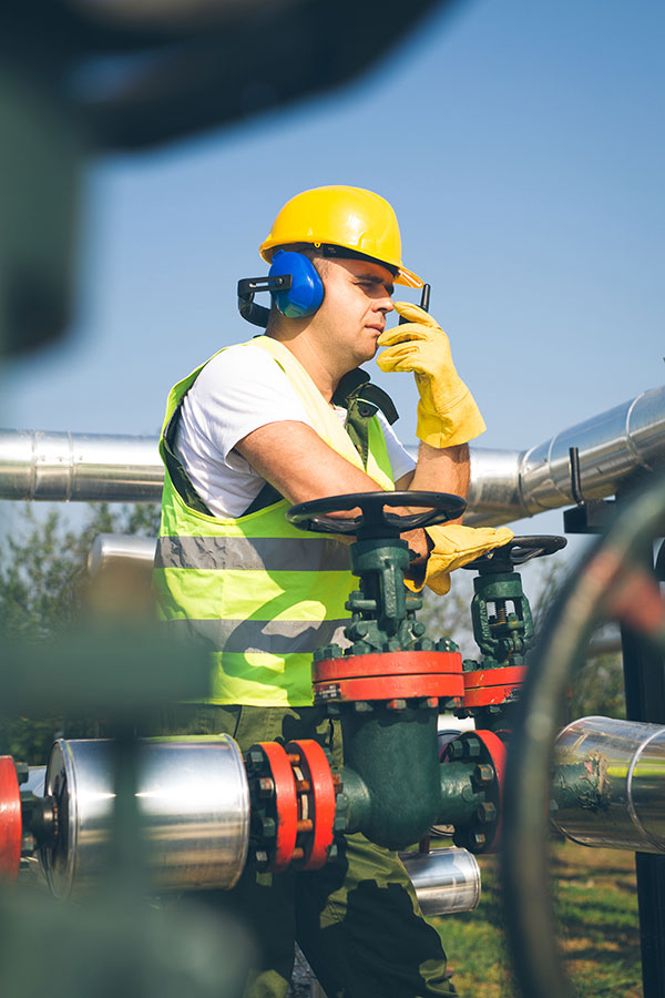 Man Wearing a Hard Hat and Safety Vest Using a Radio